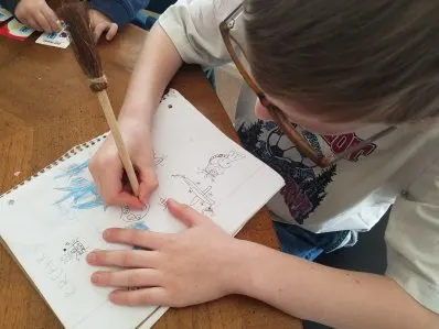 Writing Short Stories In Our Homeschool 4 Young boy with pen and notebook. He is illustrating pictures in his notebook.