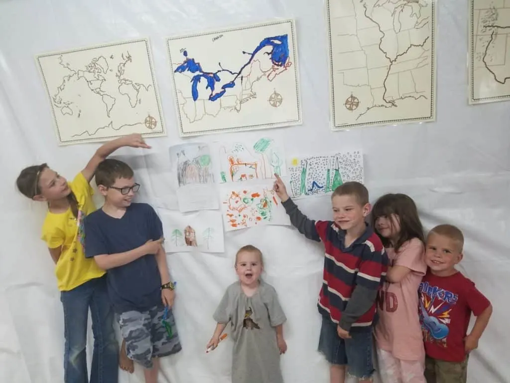 Ignite Wonder with a Charlotte Mason Inspired Geography Curriculum 6 6 homeschooled kids pointing at pictures they drew during a Charlotte Mason geography lesson