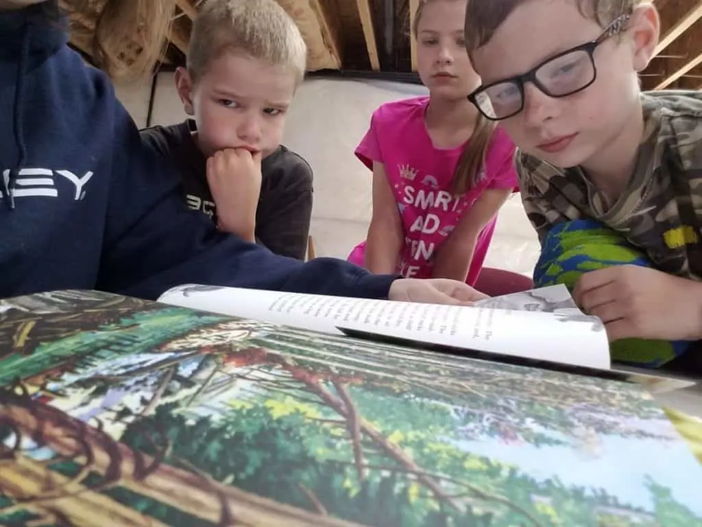 Ignite Wonder with a Charlotte Mason Inspired Geography Curriculum 7 Homeschooled kids enjoying the illustrations in the Beautiful Feet Books geography through literature pack