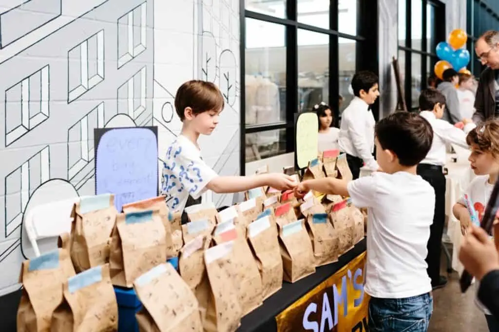 Support Your Child Entrepreneur with the Acton Children's Business Fair 3 kid entrepreneur with paper bags at a booth at an Acton Children's Business Fair