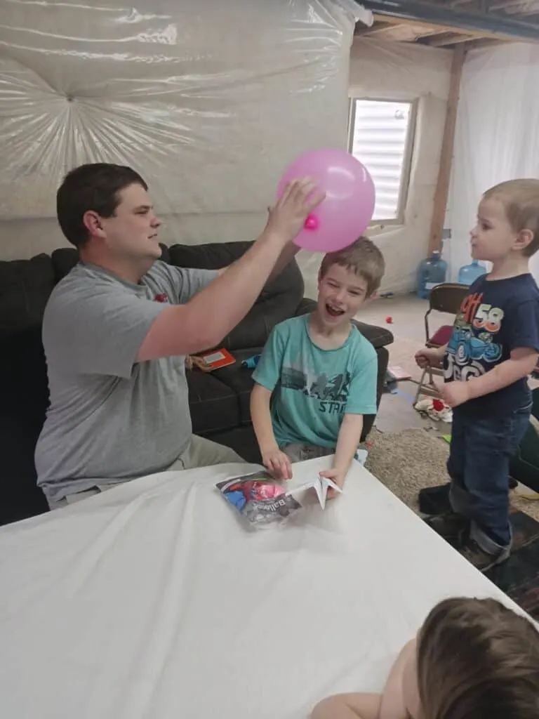 Static Electricity Experiment for Kids - Tame a Dragon with Magic 4 man rubbing pink balloon on young boy's head for a static electricity experiment