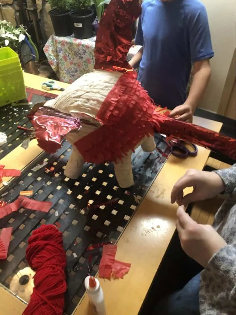 Paper Mache Dragon STEM and Craft Project Tutorial 15 layering red tissue paper onto paper mache dragon