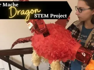 teenage girl holding completed red dragon out of paper mache