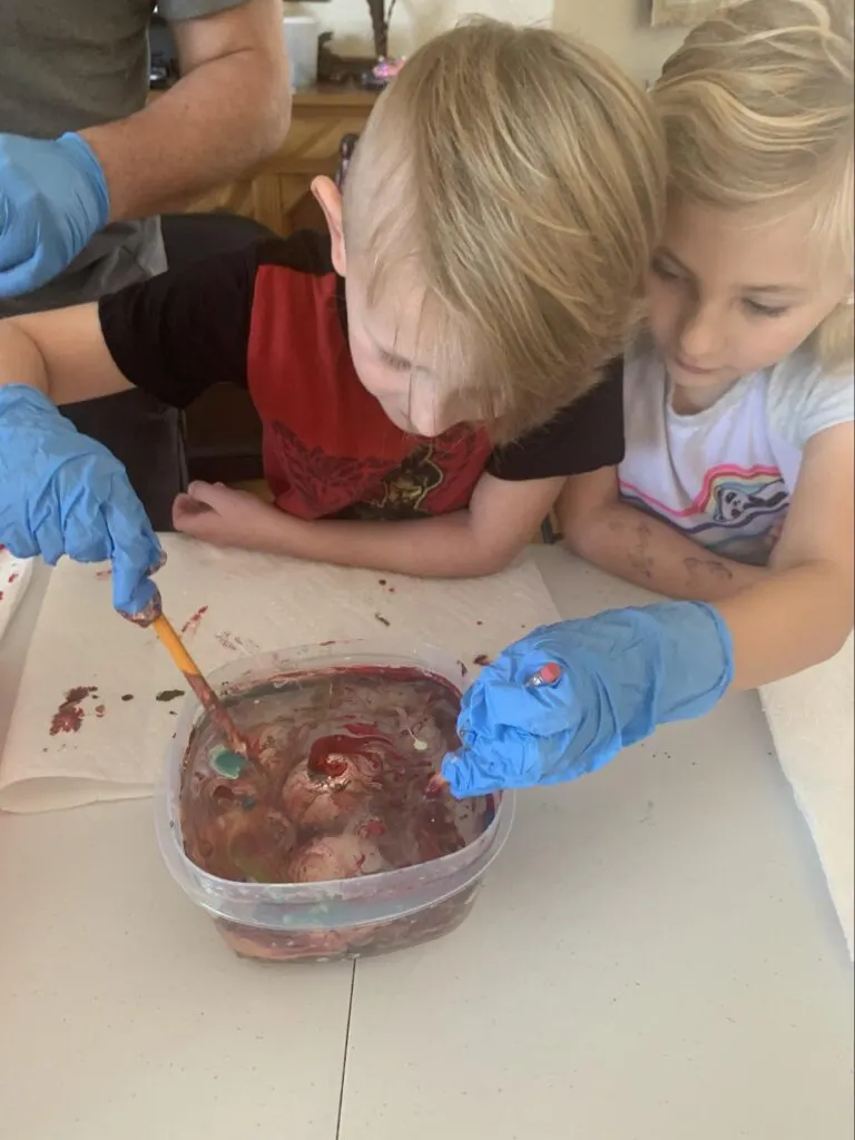 Marbled Eggs - A STEM Lesson on Density For Kids 3 two kids making marbled eggs in a bowl of water and nail polish
