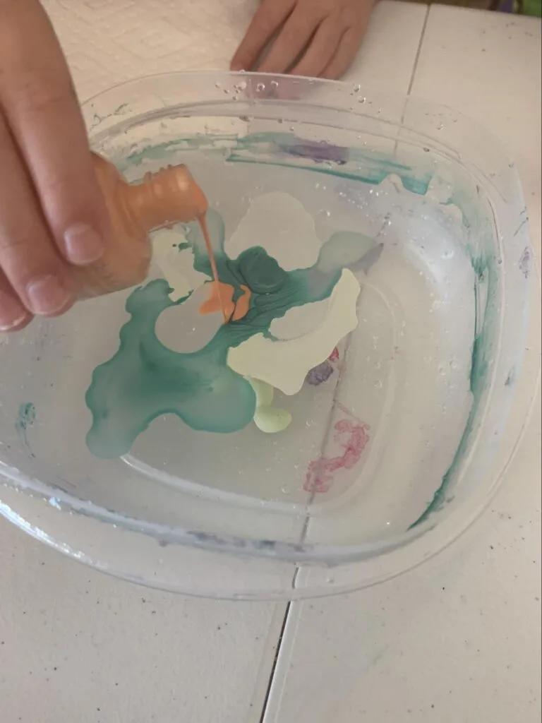 Marbled Eggs - A STEM Lesson on Density For Kids 2 pouring nail polish into a bowl of water for homemade marbled eggs