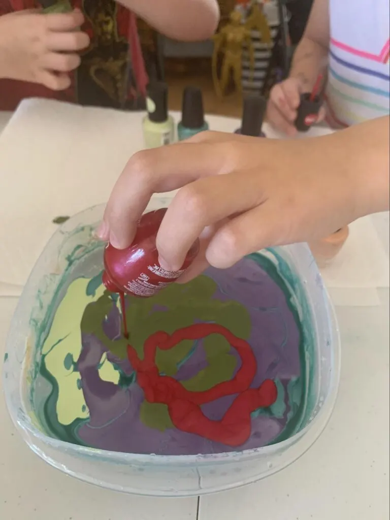 Marbled Eggs - A STEM Lesson on Density For Kids 4 holding a marbled egg over the bowl of water and nail polish