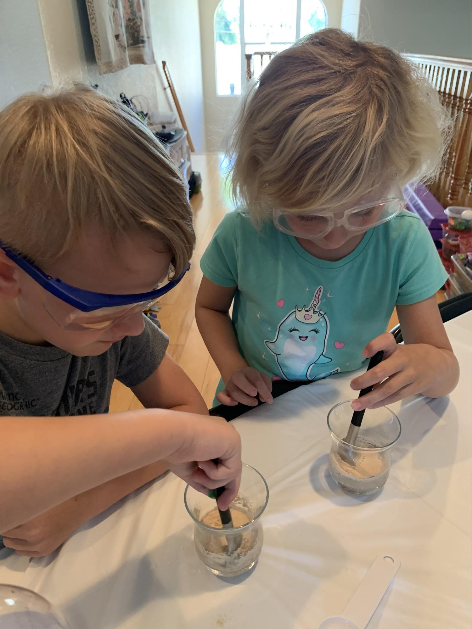 two little kids mixing yeast into water for the Elephant Toothpaste experiment